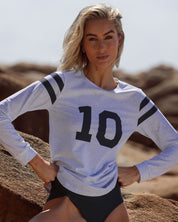 Model relaxing on beach wearing UPF50+ rash vest with exclusive Perfect 10 print