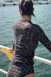 Back view of the ACQUA leopard print zip long sleeve UPF50+ rashie with gold zipper, standing on a wharf.