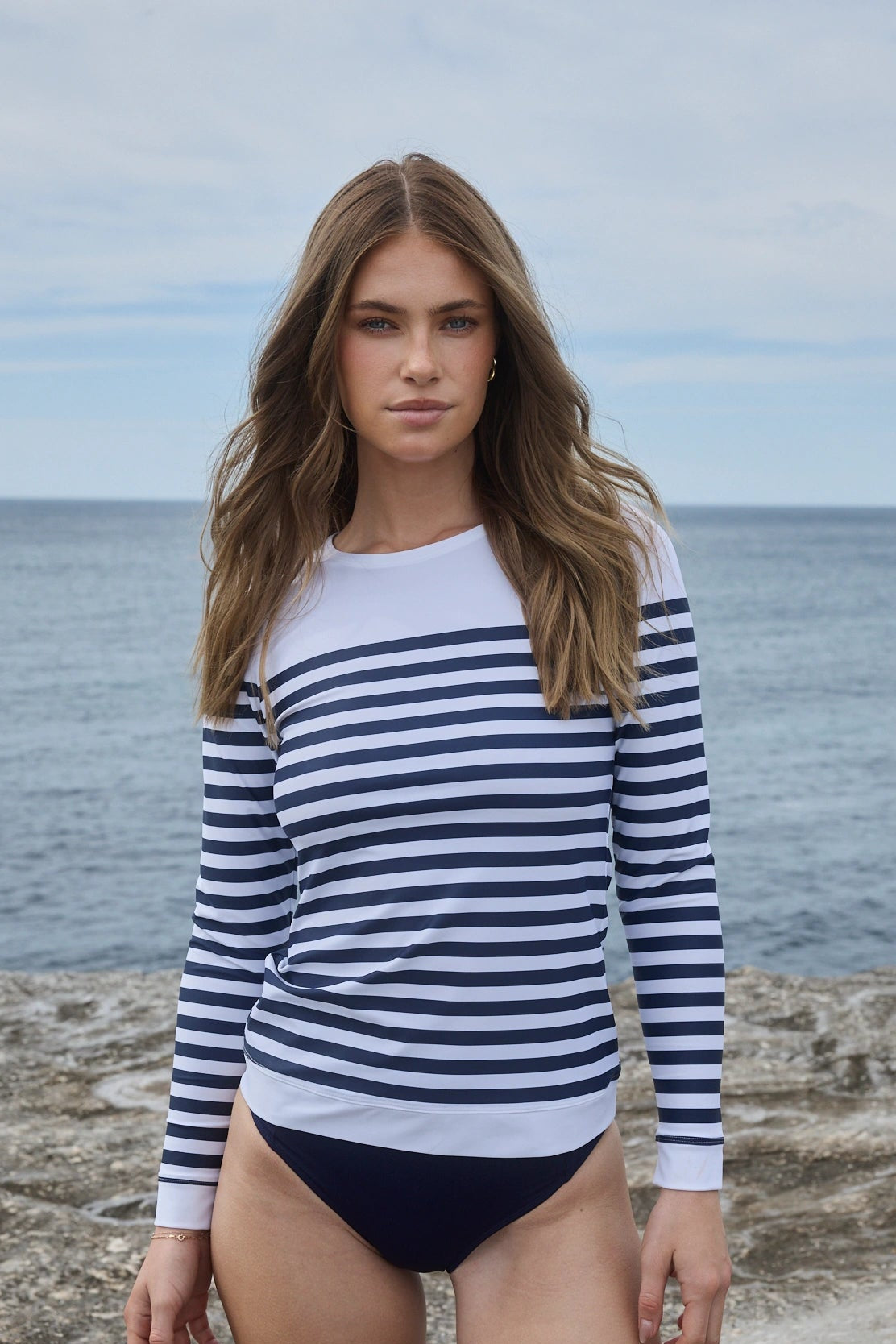 Woman wearing striped UPF50+ rashguard by The ACQUA Brand at the beach