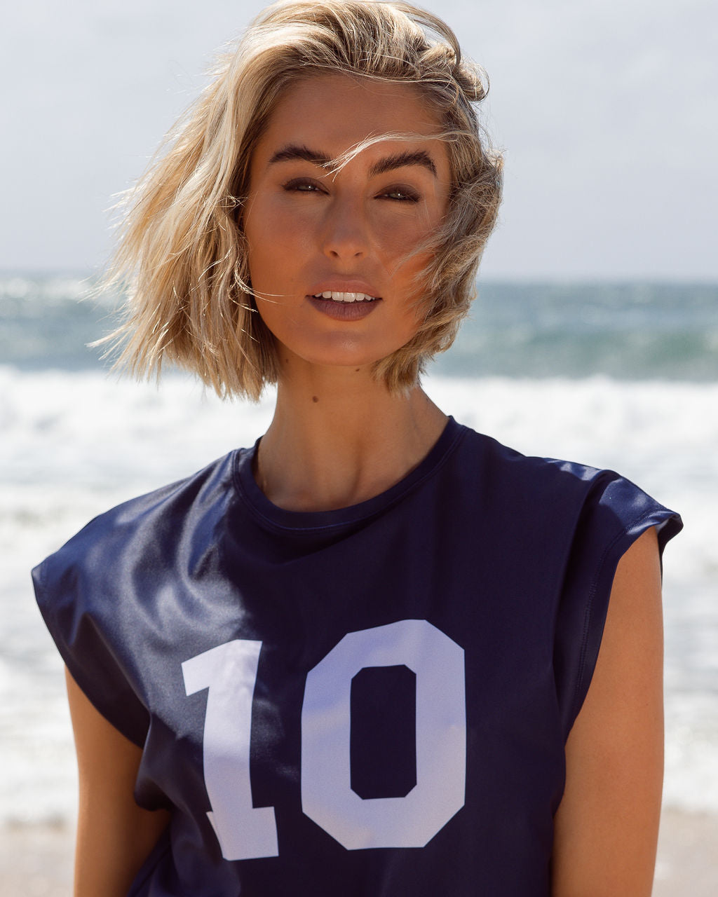Model on beach wearing navy Perfect 10 relaxed UPF50+ rash vest showing exclusive print